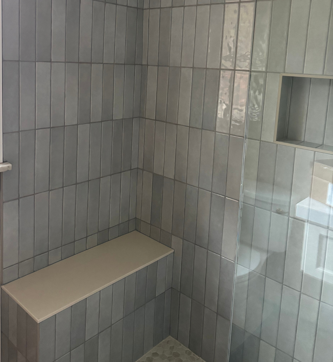 Light gray custom tiled shower with bench