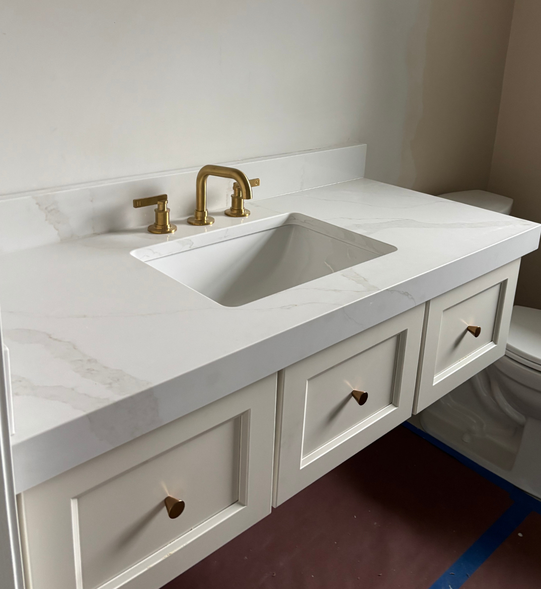 White countertop on a vanity with gold bath fixtures